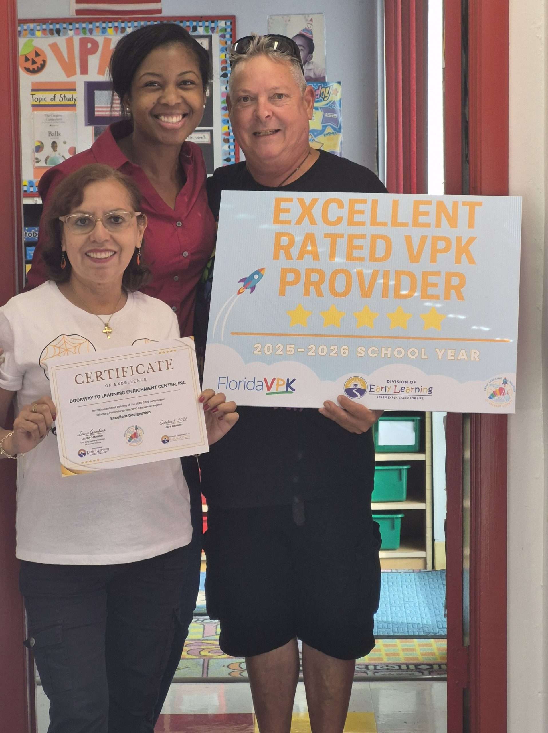 Doorway to Learning staff members celebrating their Excellent Rated VPK Provider recognition, holding an award certificate and recognition sign.